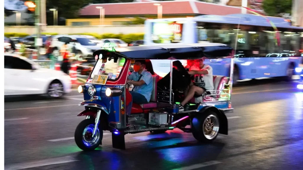 Traveler using eSIM on phone while riding a tuk tuk in Bangkok