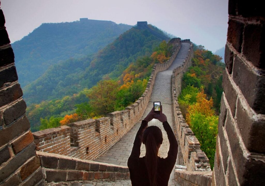 Traveler using phone at Great Wall highlighting need for china hong kong esim vs pocket wifi coverage