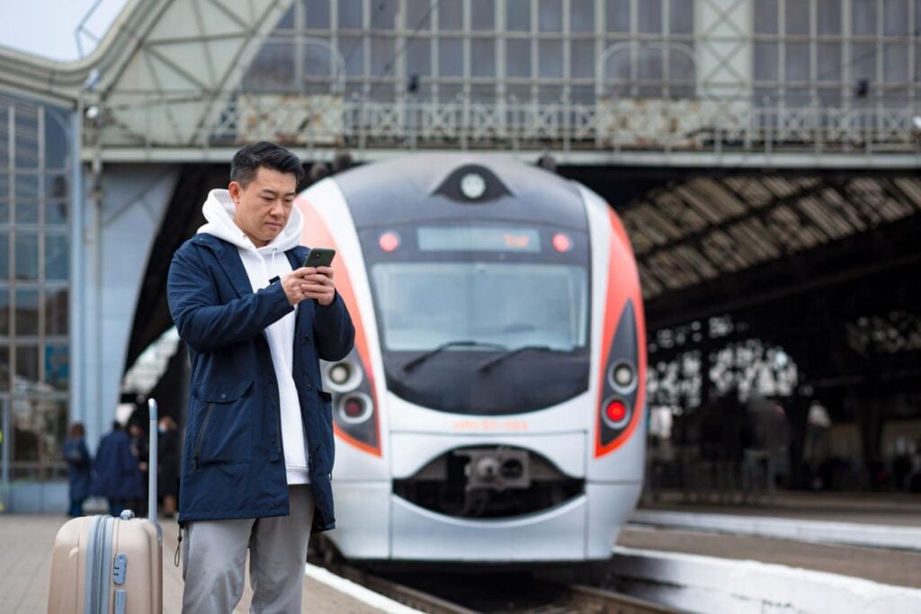Traveler booking train using china hong kong travel apps on smartphone during trip
